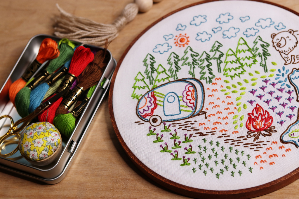 outdoor-themed embroidery pattern with camper, campfire, bears and forest landscape