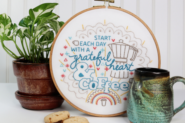 coffee-inspired embroidery kit displayed alongside plant and mug on side table