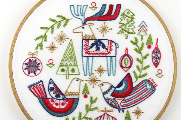 Holiday-themed embroidery project uses chain stitch to fill in sections of folk-art birds and reindeer
