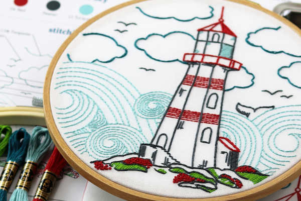 embroidery project with lighthouse on rocky hills in front of rolling waves