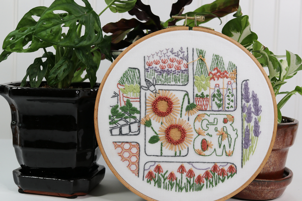 garden-themed embroidered hoop art displayed with houseplants 