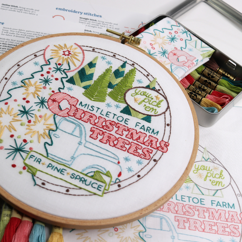 embroidery kit with holiday-themed design, including embroidery floss, pattern, hoop and storage tin.