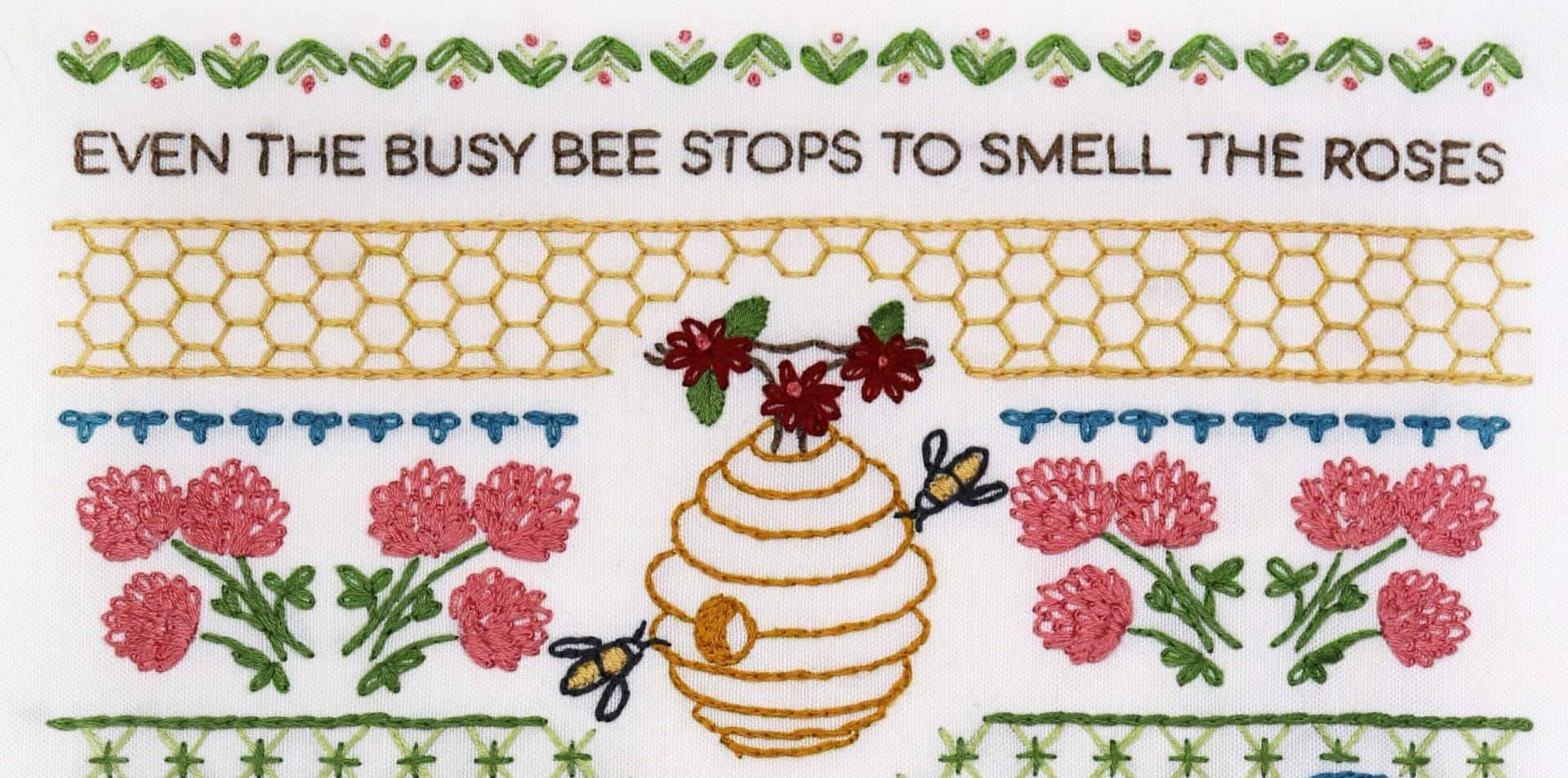 Embroidered detail from traditional embroidery stitch sampler with honeybee themes