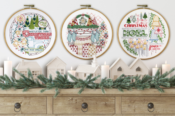 three holiday embroidery projects hanging on the wall as decoration