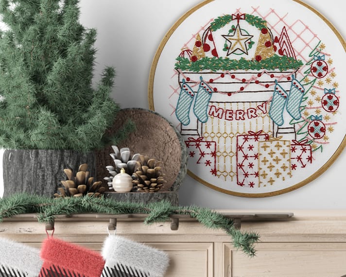 Embroidered Christmas hoop art hung over stockings. 