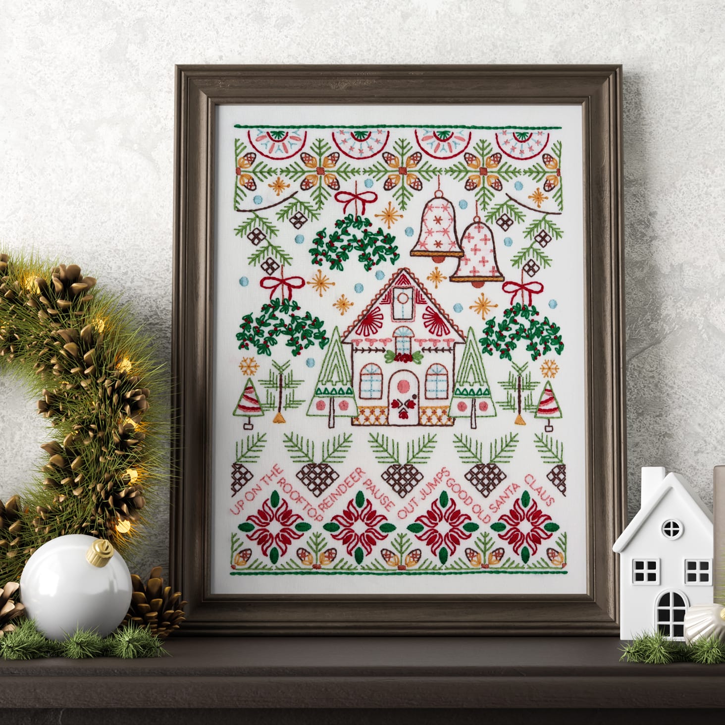 framed Christmas Pines embroidery displayed on mantle with holiday decor